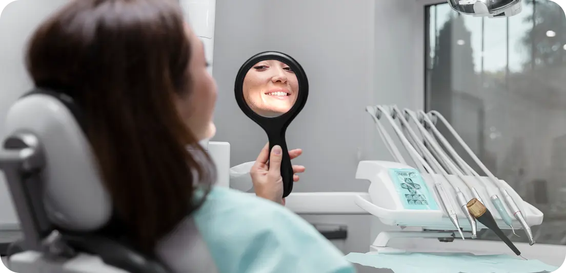 Woman smiling in mirror at her teeth