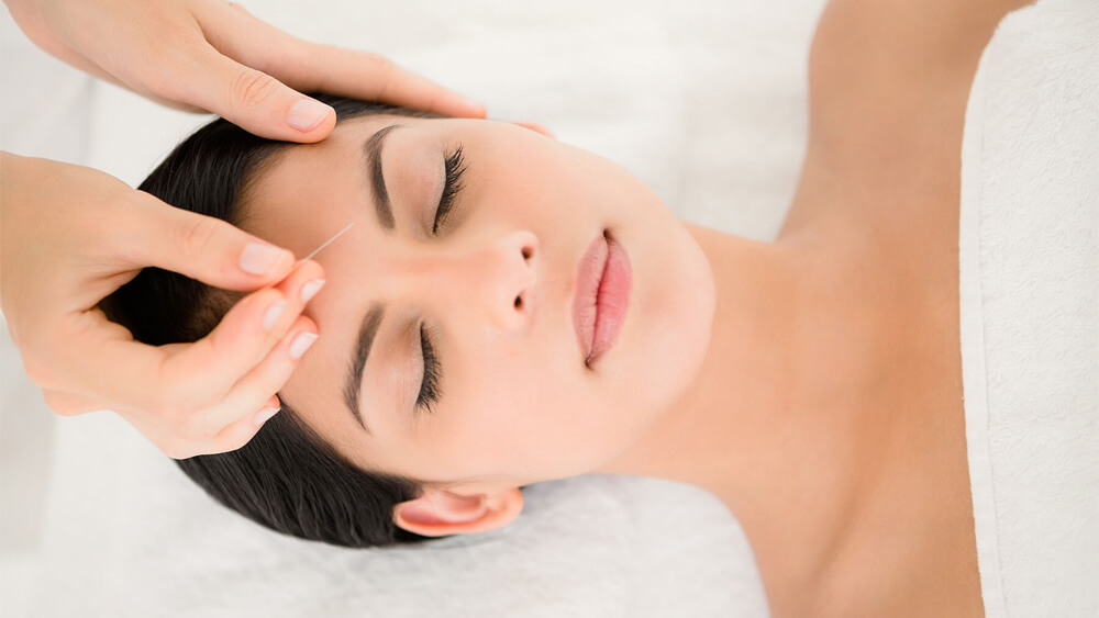a woman is doing cosmetic acupuncture calmly