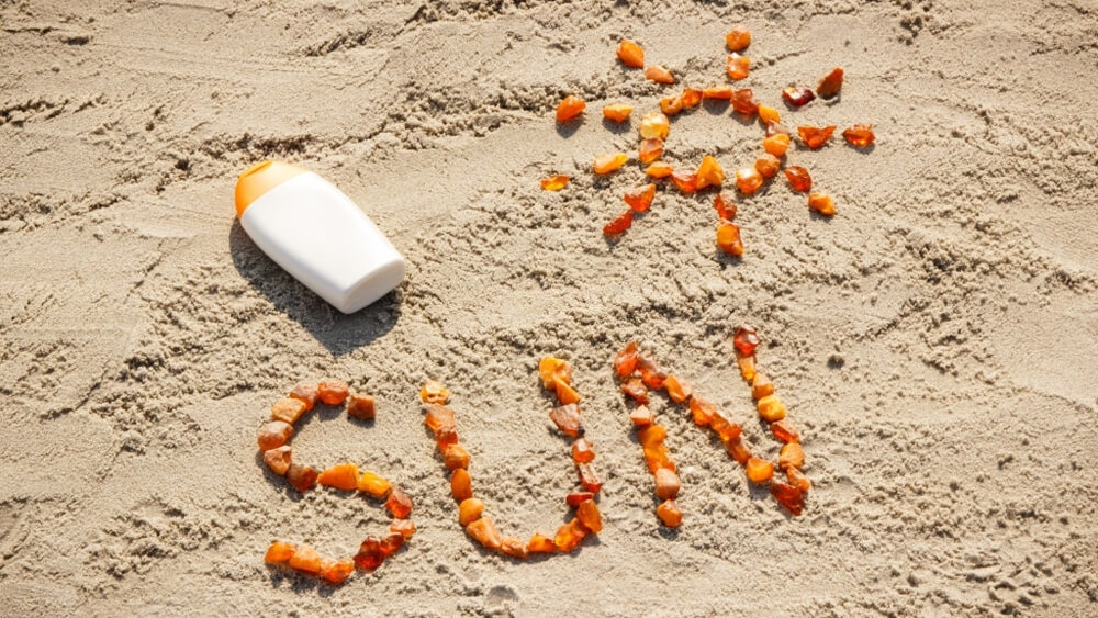 Word and shape of sun lotion on the sand at the beach