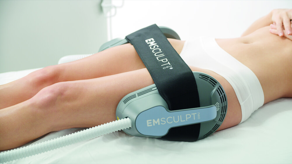 Woman is under EMSculpt Neo device