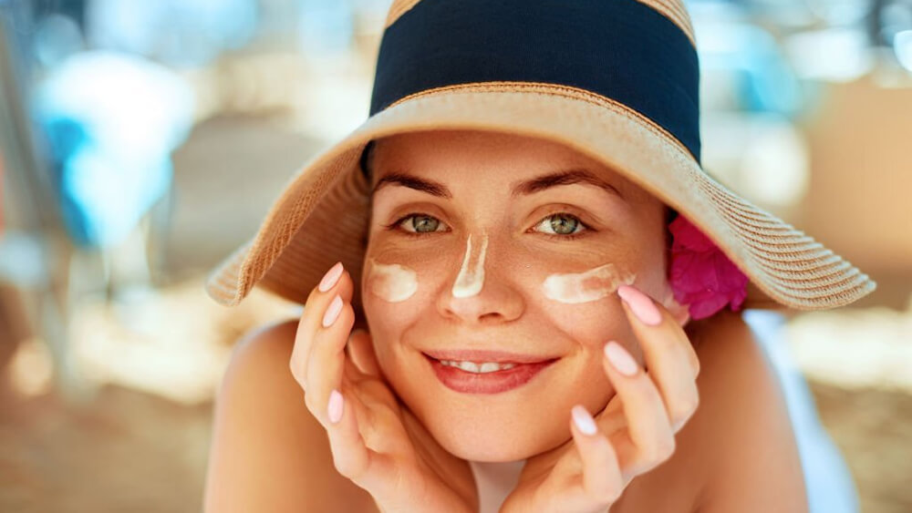 Woman applying sunscreen and touching her face