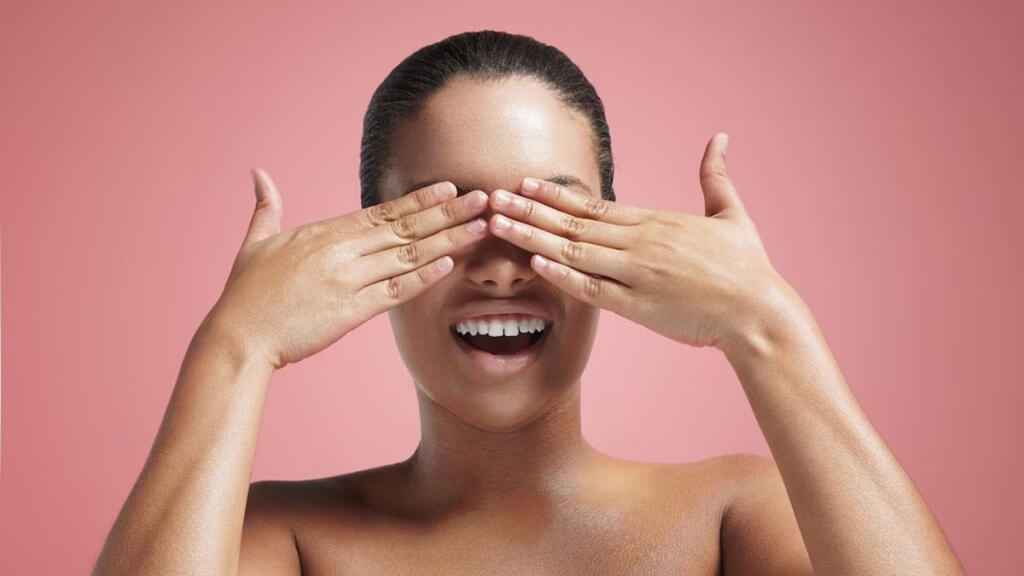 Smiling woman closed her eyes with hand