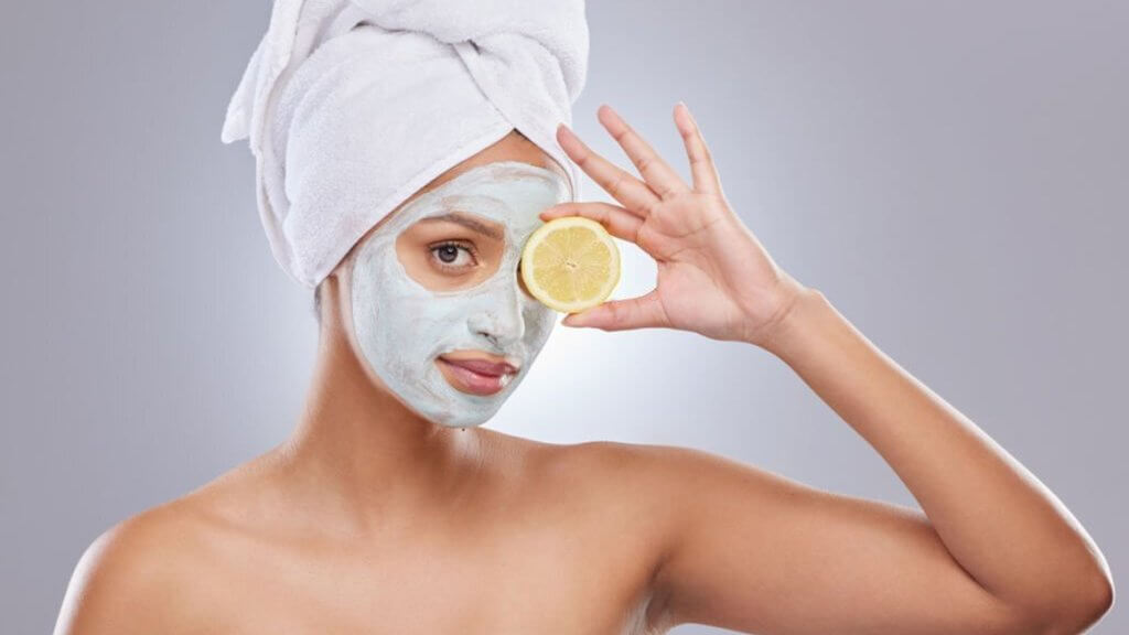 Woman wearing face mask and holding a lemon