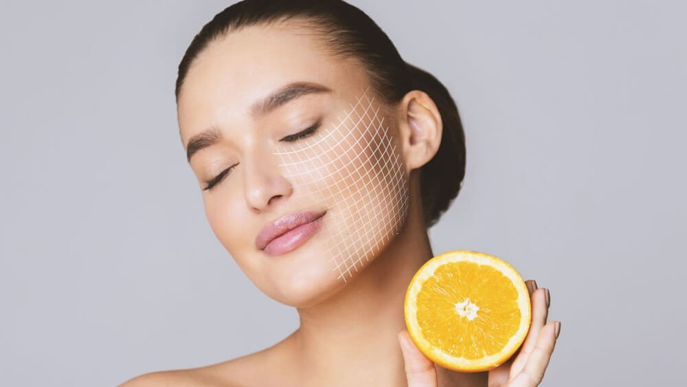 Woman with closed eyes holding half of orange as the vitamin C source