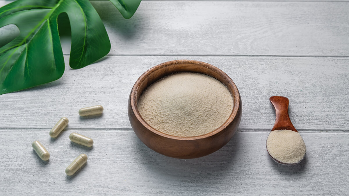 Collagen powder in a bowl and a spoon on wooden table