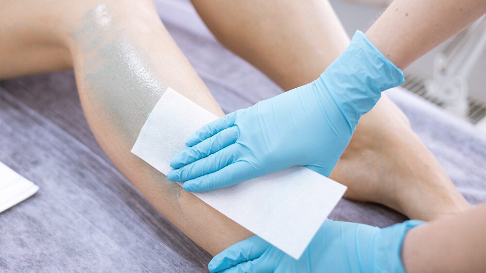 Female legs hair removal with wax in beauty salon