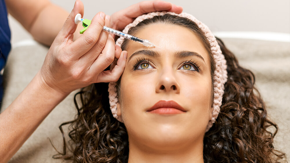 Woman getting Botox injection on her forehead