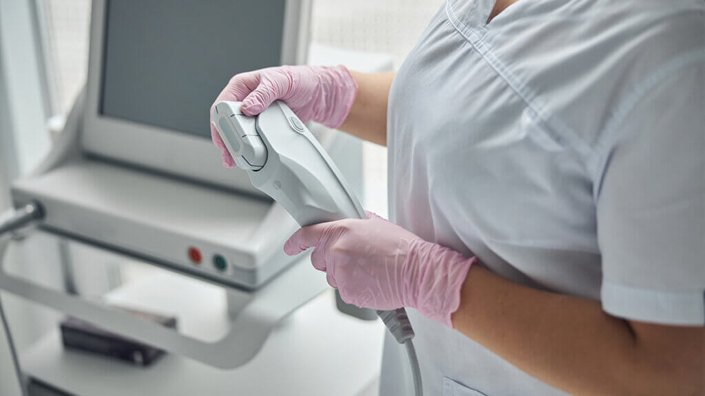 Young female beautician holding IPL laser device