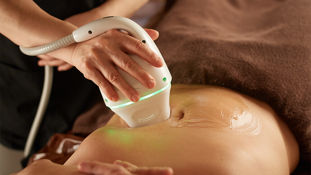 Closeup of a woman's belly under body contouring treatment