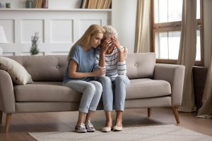 Image of two ladies sitting on a couch, hugged together