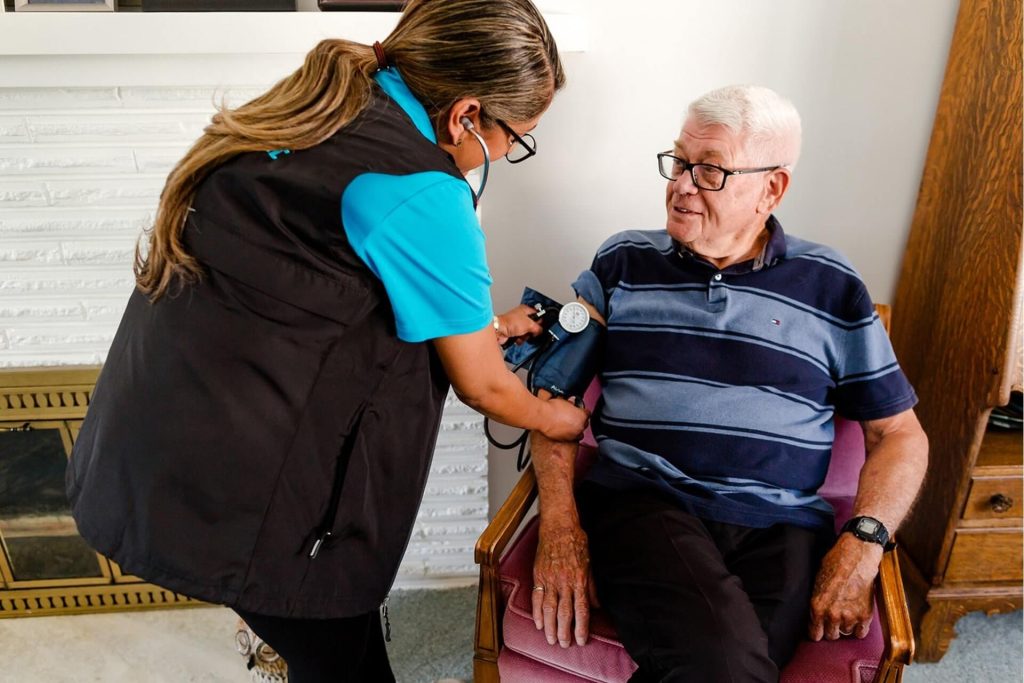 A woman is taking the blood pressure of an elderly man