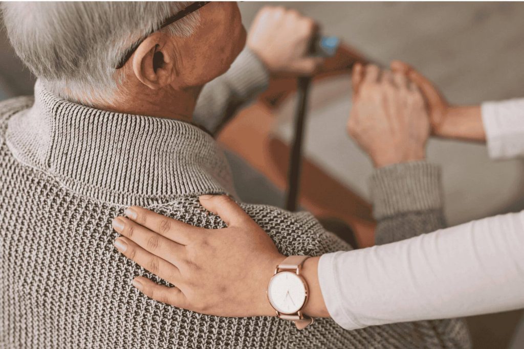 Image of a hand on a seniors back.